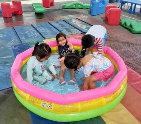 Children make a splash during outdoor water activities at Hope Childcare Center.